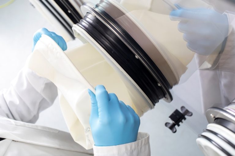 laboratory analyst placing a gauntlets on a laboratory safety enclosure